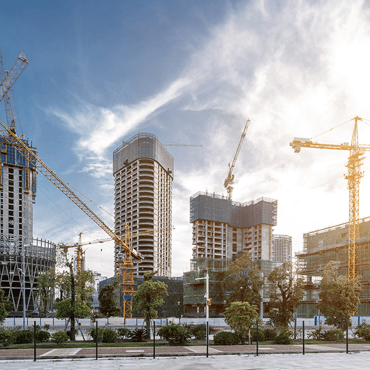 Cranes erecting three buildings in the middle of a cityscape