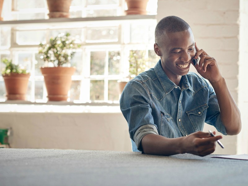 A smiling male in casual wear making a phone call
