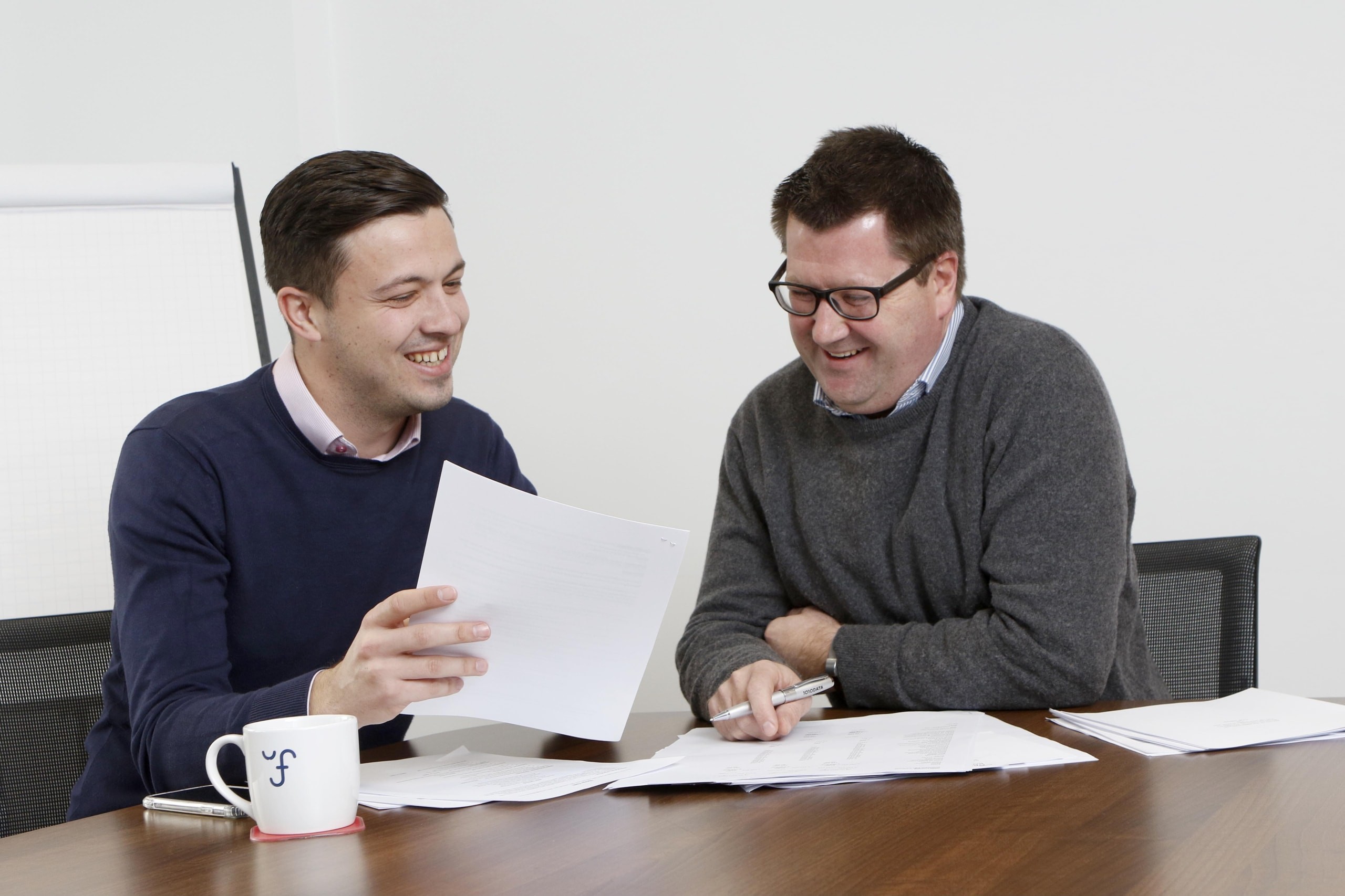 Business meeting between two men looking at documents on a desk