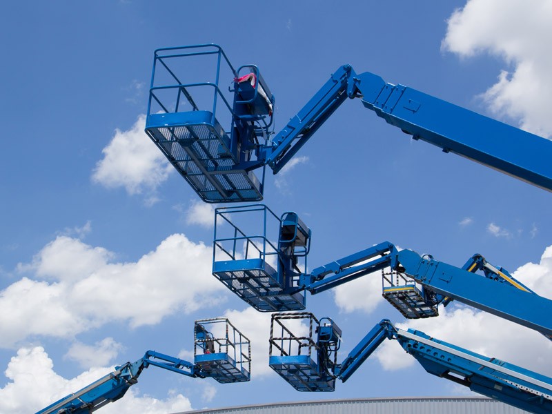4 cranes with buckets lifted on to the skyline against a blue sky