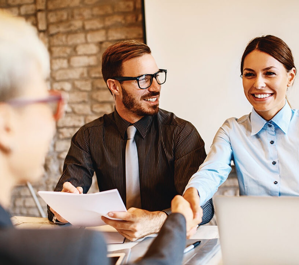 Female employee shaking client's hand over a desk