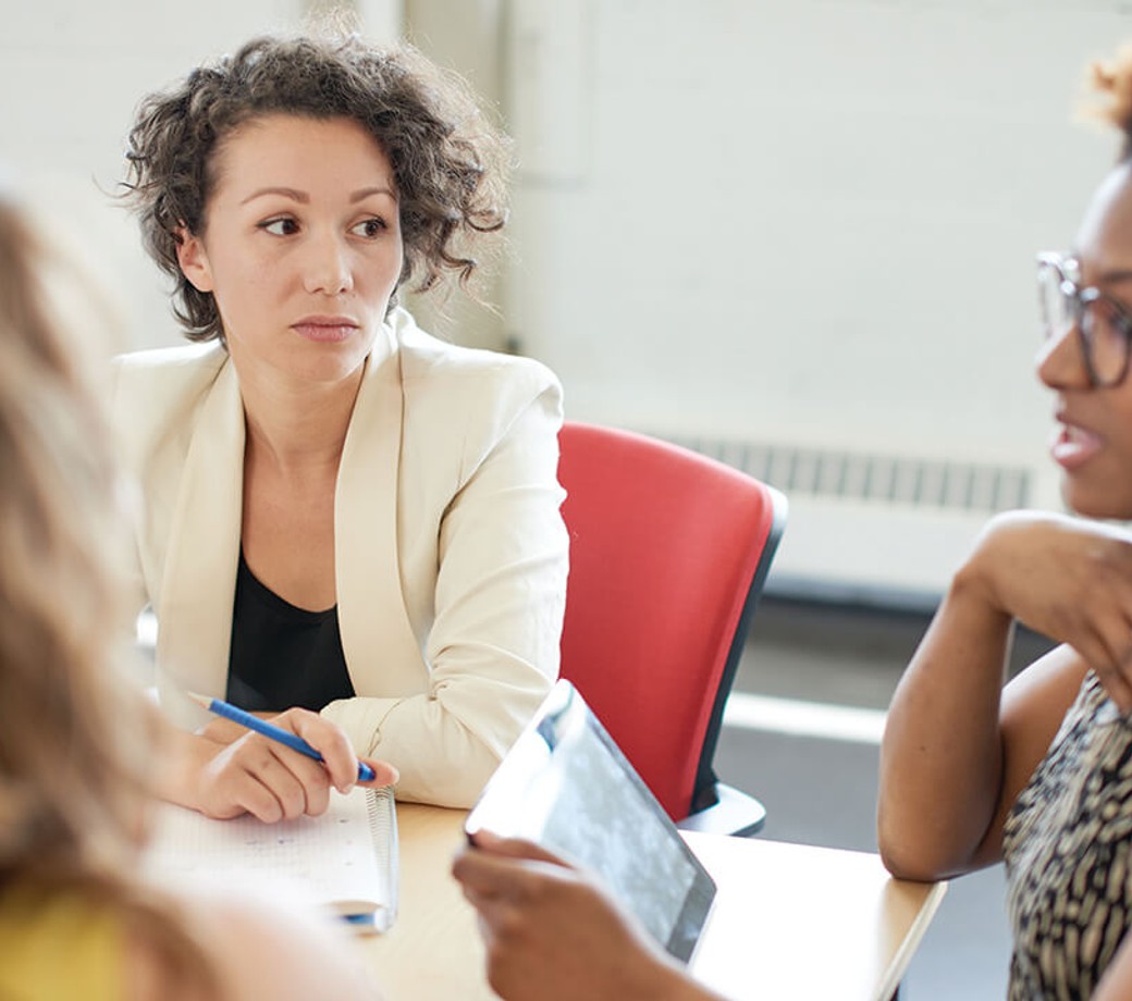 Three female employees having a conversation in a meeting room