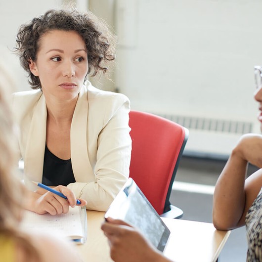 Three female employees having a conversation in a meeting room