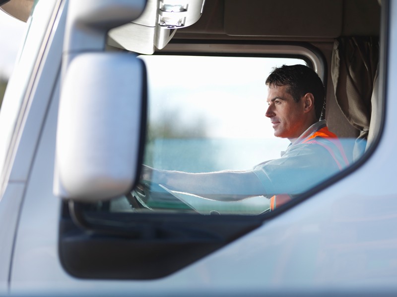 A man in a high vis jacket driving a white truck