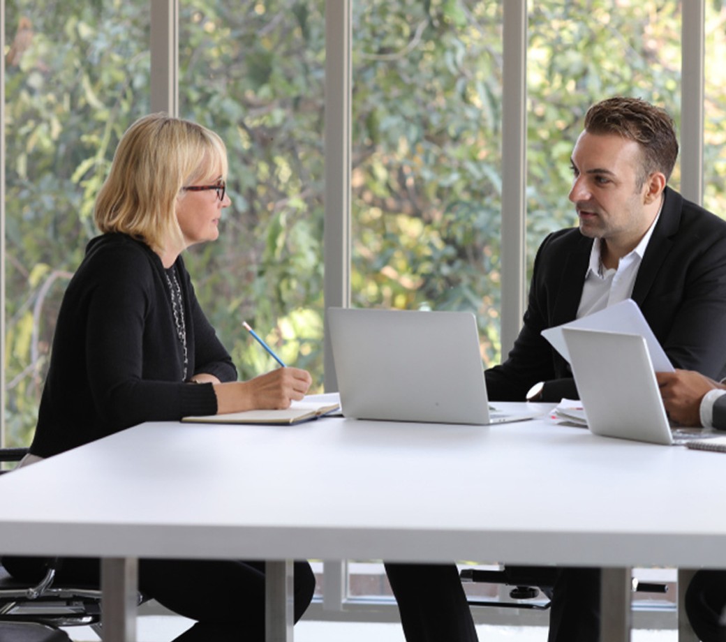 Three professionals in a well lit meeting room discussing documents